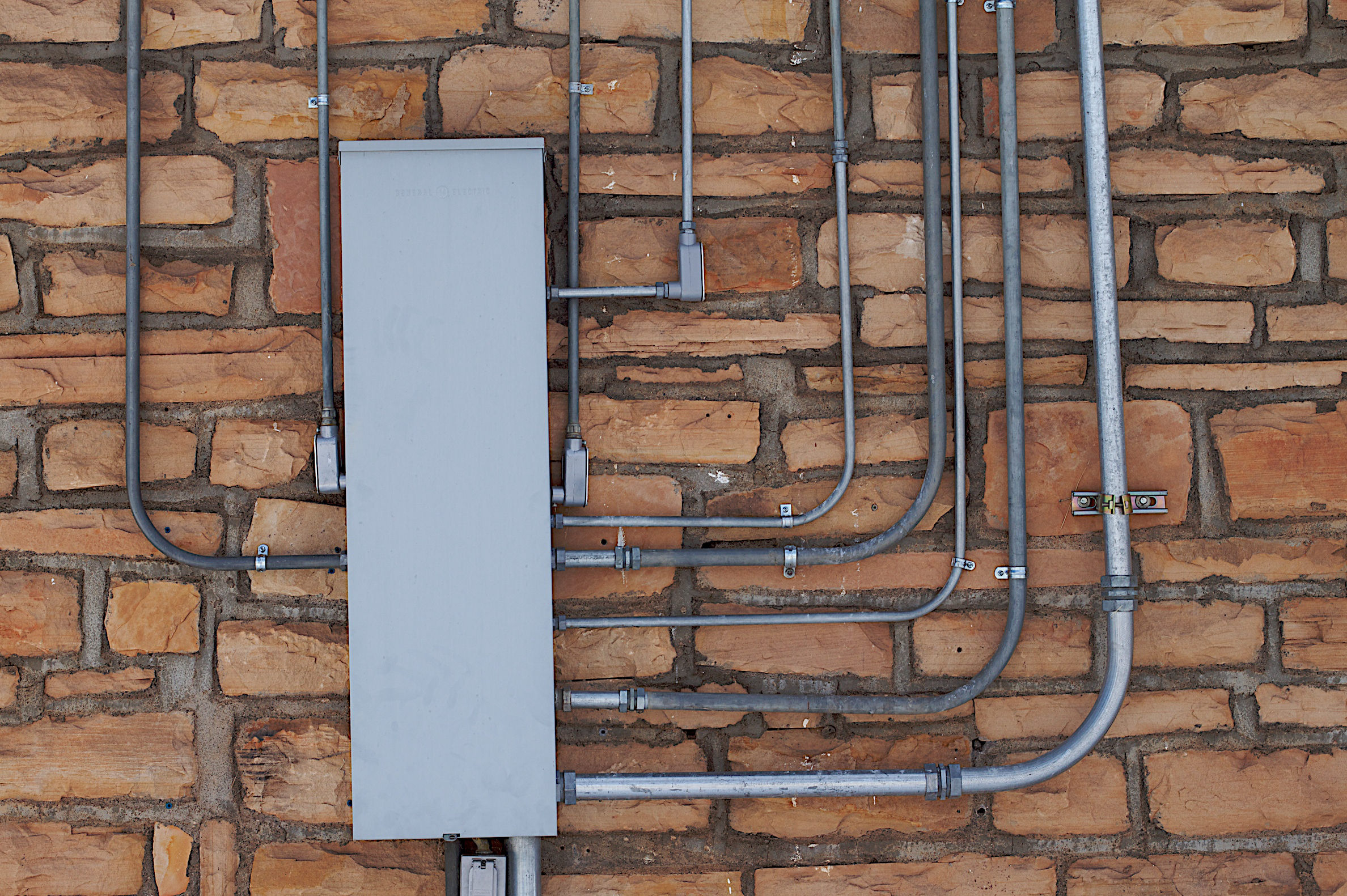 Tubos eléctricos recorren una pared de ladrillo