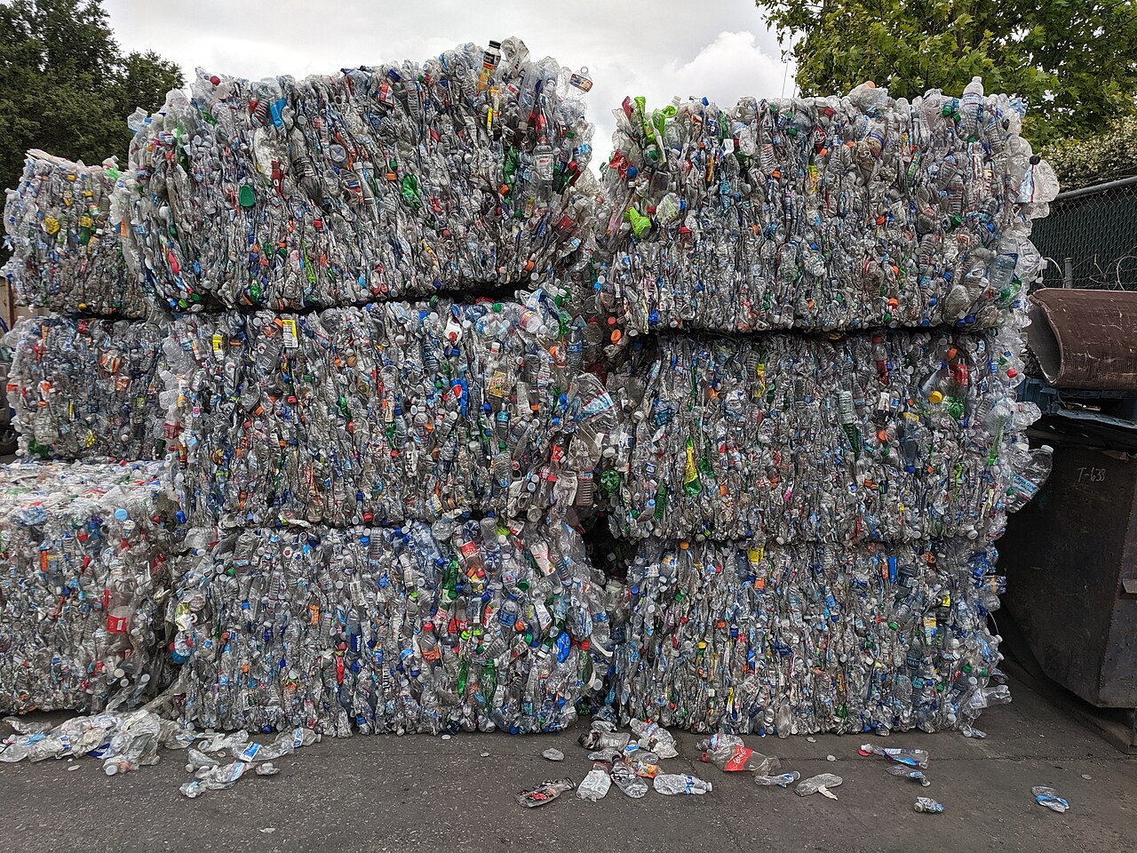 Stacked bales of crushed plastic drink bottles at a recycling yard.