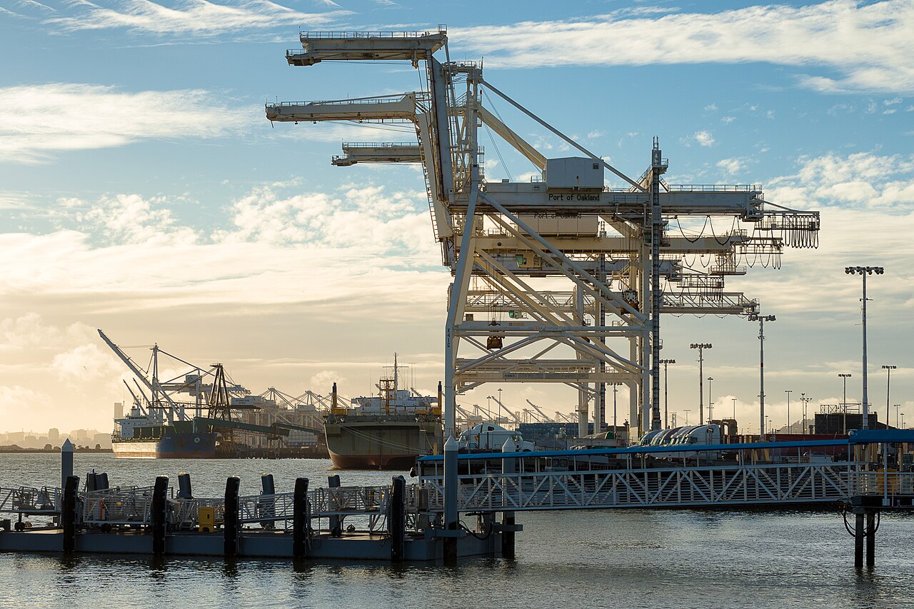 Giant container cranes at the Port of Oakland, with ships at the quay behind.