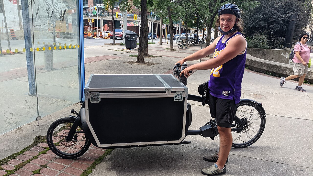 A rider beside an electric cargo bike with a large insulated box used for a butcher's deliveries in Toronto.