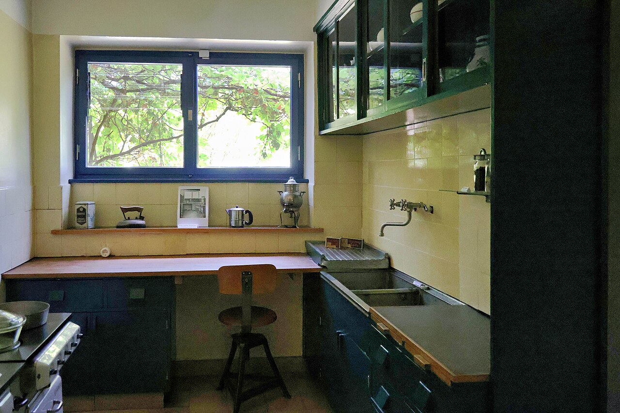 A Frankfurt Kitchen with blue cabinets, a window counter and a stool, in the Ernst-May-Haus.