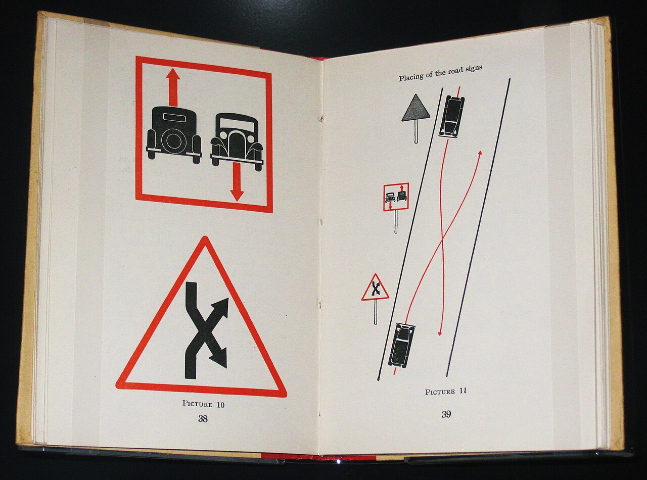 An open Isotype book showing road-sign pictures in red and black.