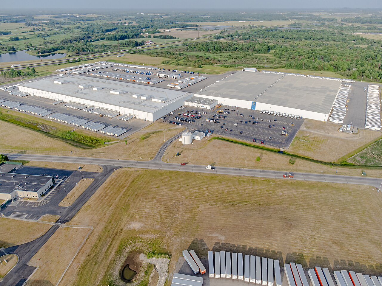 Aerial view of a huge Walmart distribution centre with rows of truck trailers in open country.