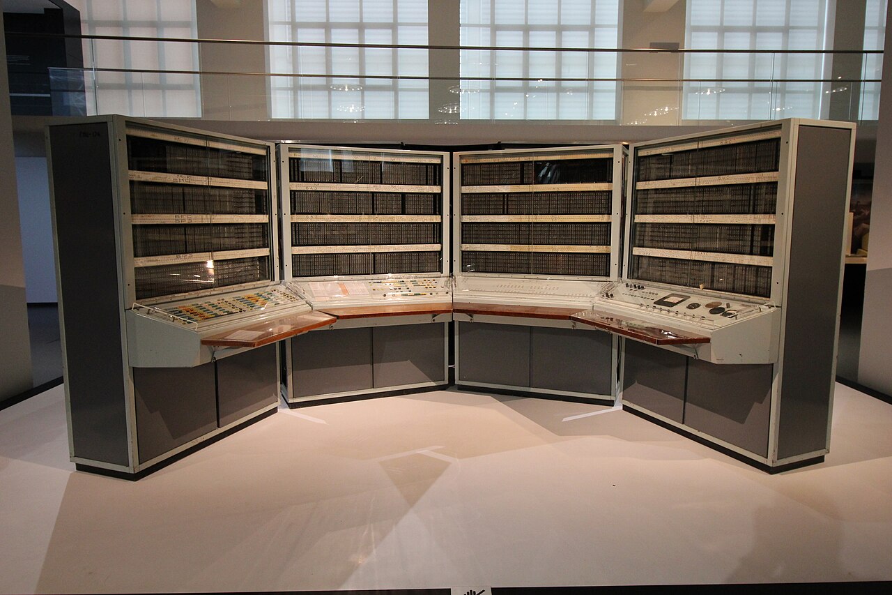 The grey cabinets and control desks of a BESM-6 Soviet computer on display in a museum.