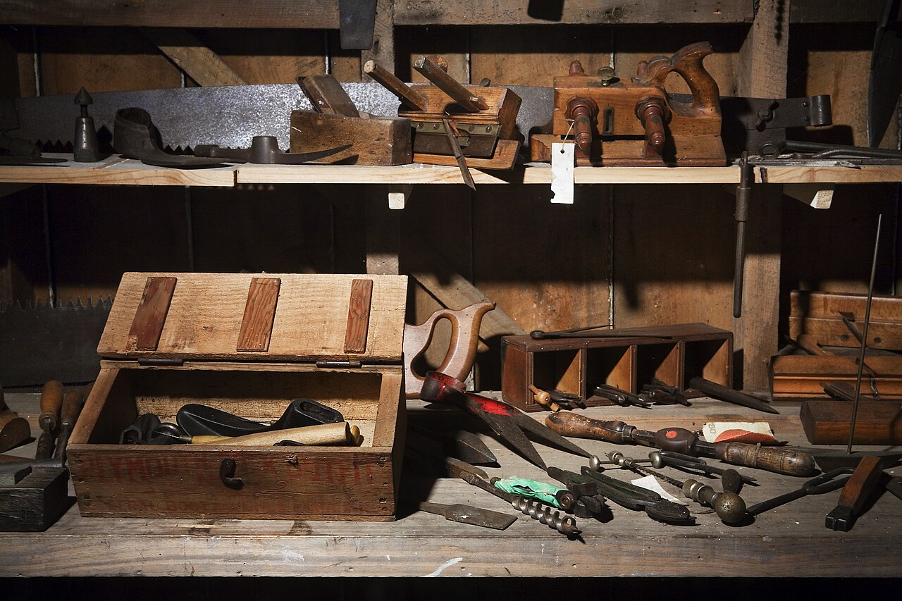 A 19th century carpenter's workbench with saws, planes, chisels and a wooden toolbox.